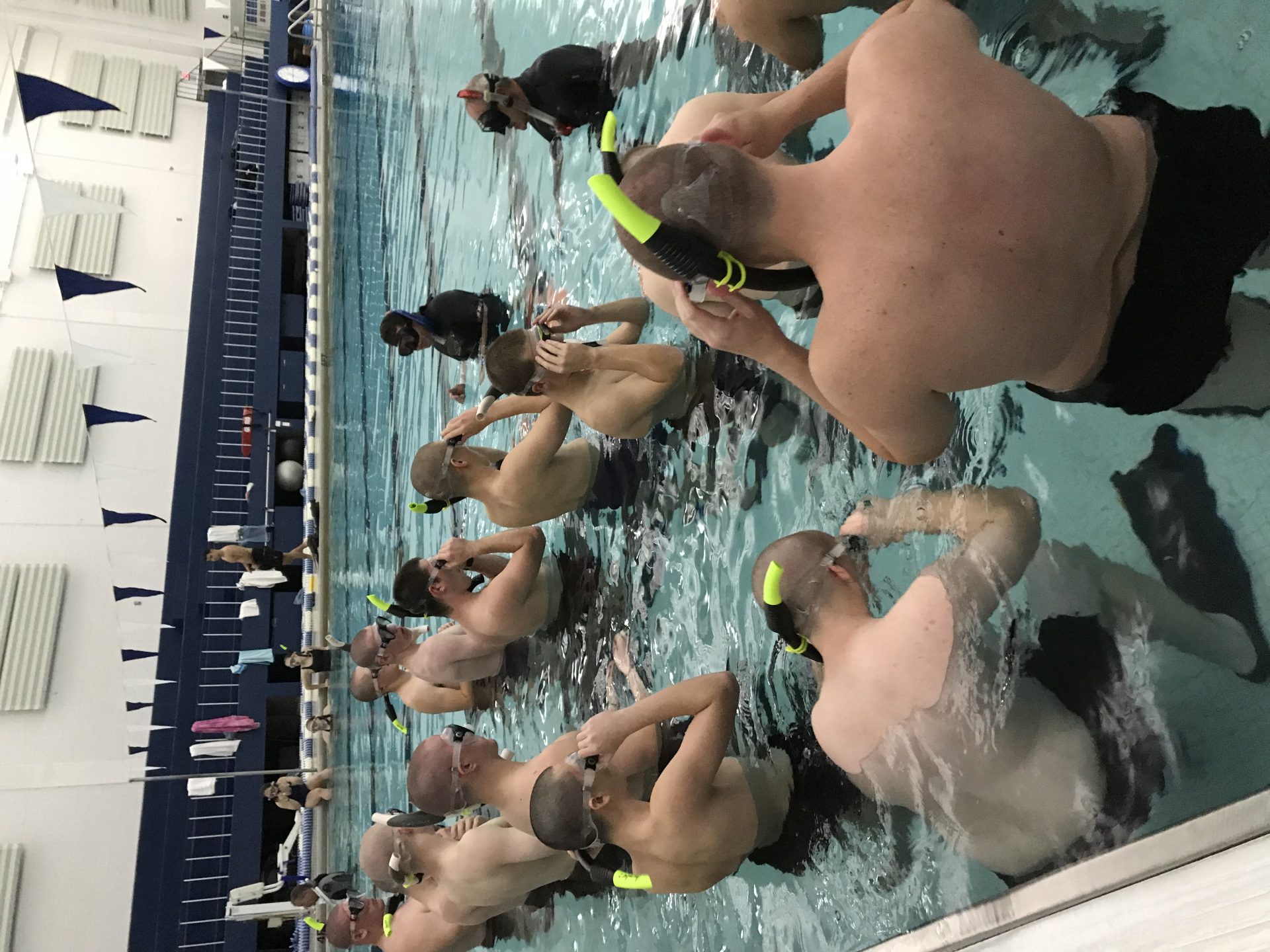 scuba diver instructors teaching how to breathe underwater in pool
