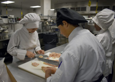 Culinary students cutting meat