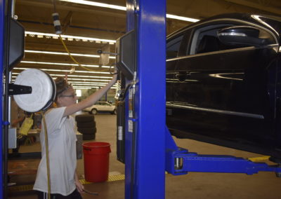 Automotive student using a lift to inspect under the car