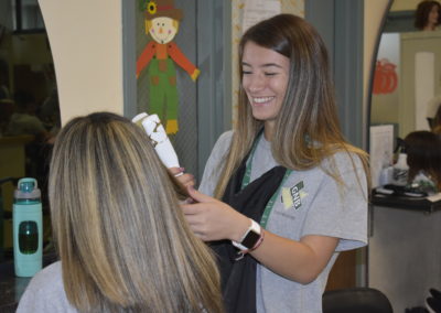 Happy cosmetology student straightening hair