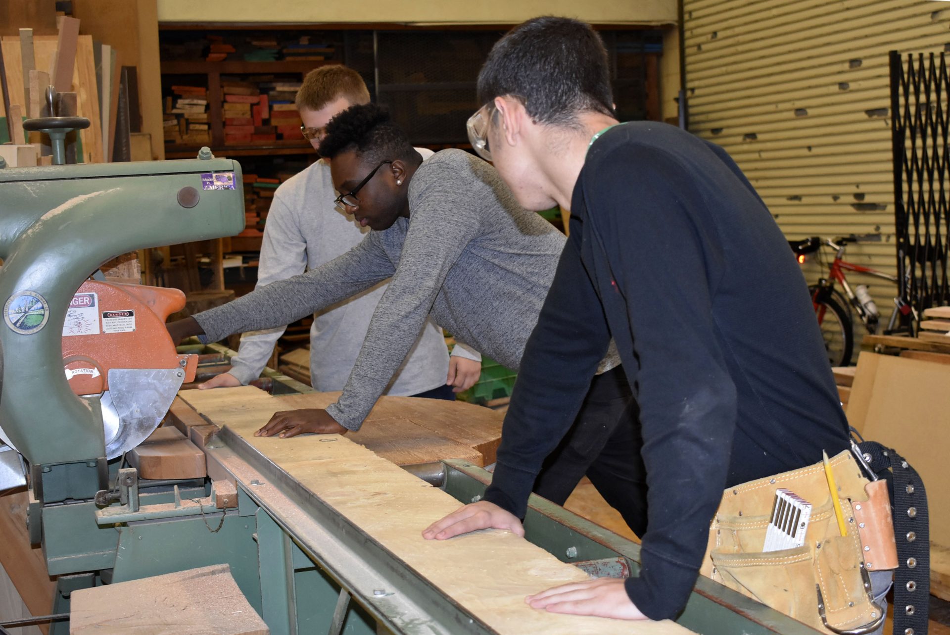 carpentry students cutting a piece of wood