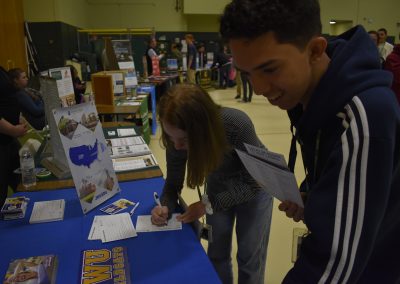 Student Looking At College While Other Student Signs College Paper