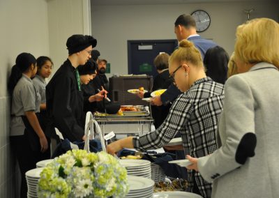 students serving food and people getting plates