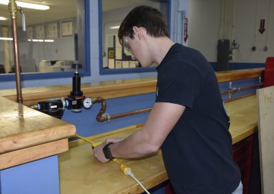 jack holding a hose working on something in shop