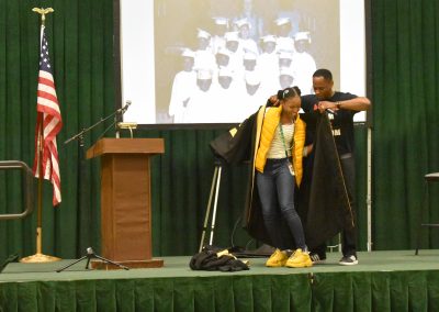 Dr Brown helps put the robe on a student