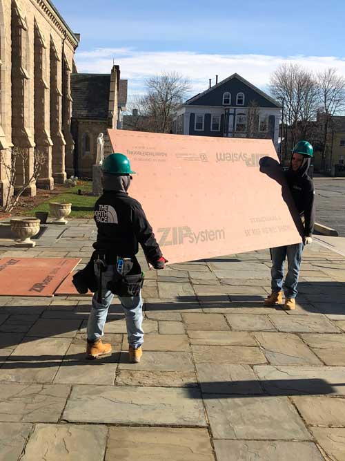 occjan1 Off Campus Construction students carrying plywood