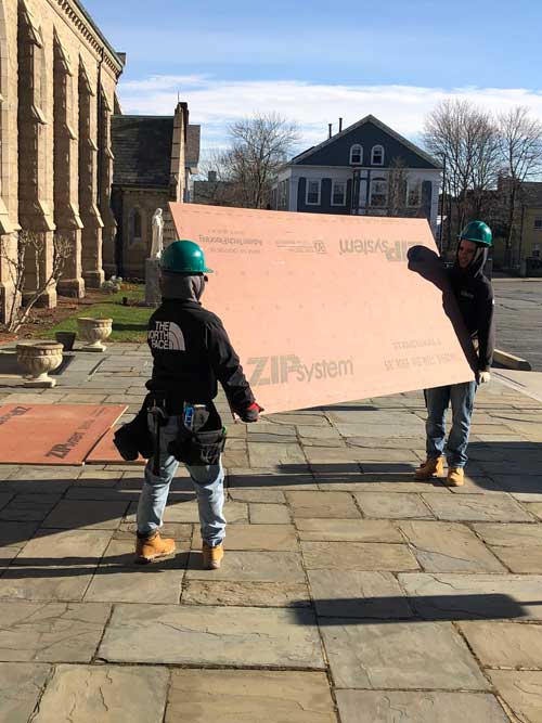 Off Campus Construction students carrying plywood