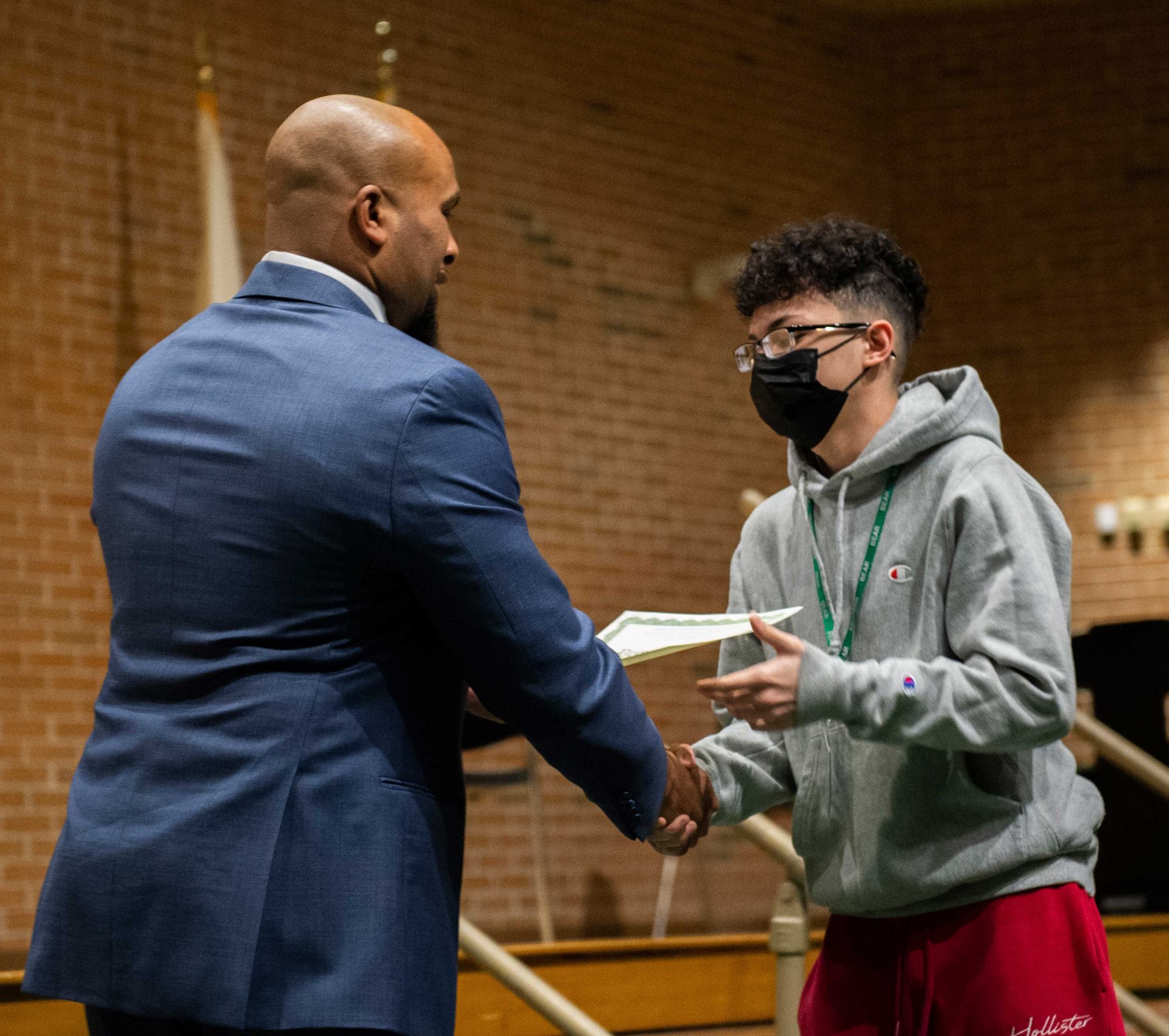 boy with gray sweater and mask shaking mr williams hand