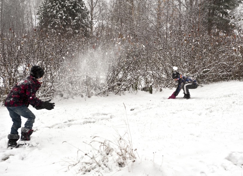 Children playing outdoors at winter time throwing snow balls at each other