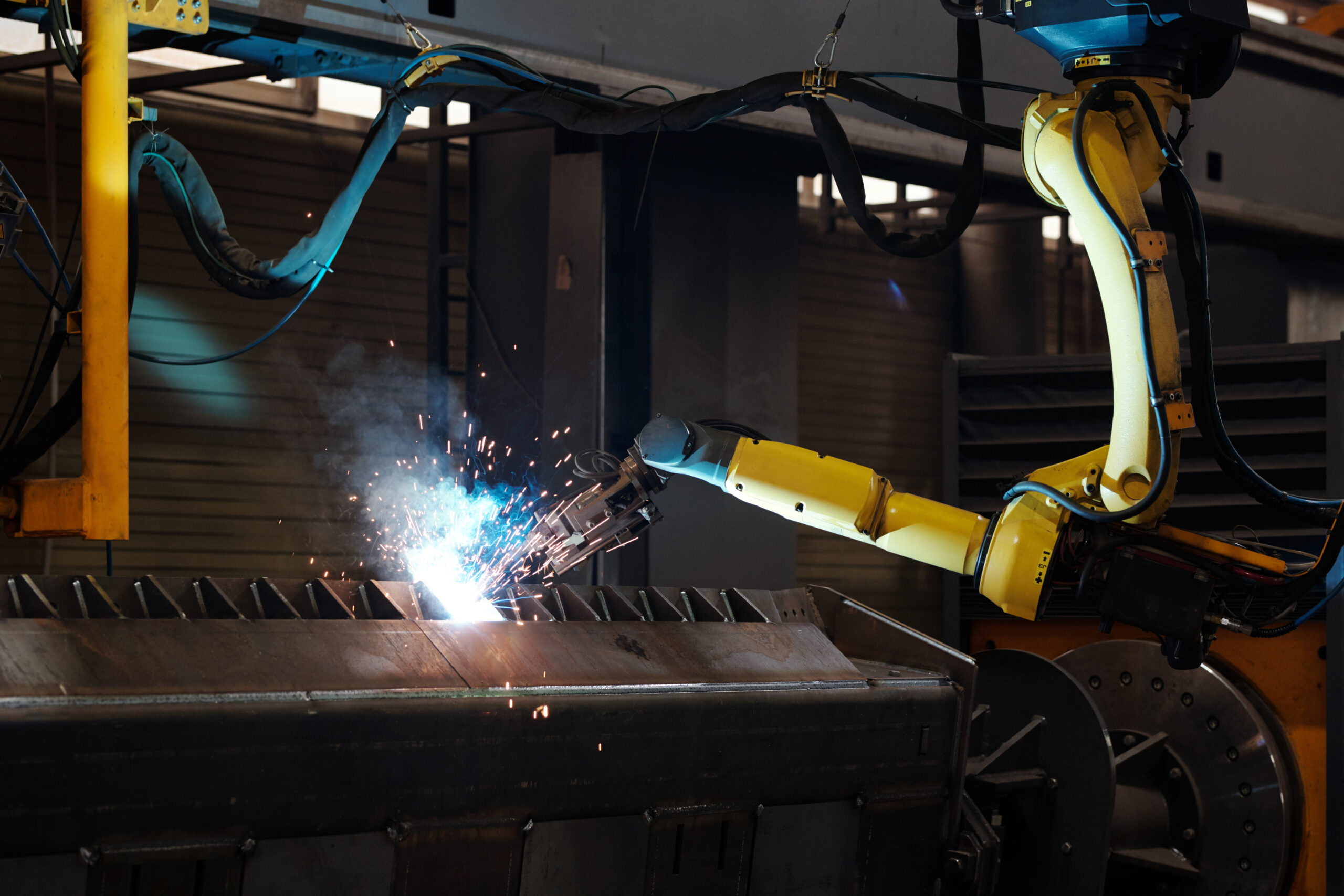 Yellow Robotic arm performing mechanical engineering producing sparks