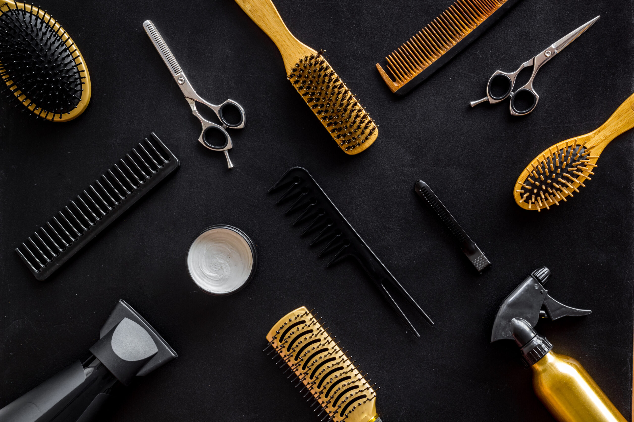 square photo of various hair dresser tools on a black background.